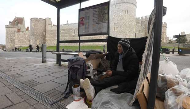 Stuart, a homeless man, sits under a bus shelter where he sleeps opposite Windsor Castle in Windsor, Britain