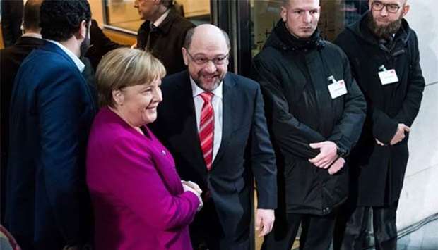 German Chancellor Angela Merkel, leader of the Christian Democratic Union (CDU), shakes hands with Martin Schulz, leader of SPD party, as they arrive for a meeting in Berlin on Sunday.