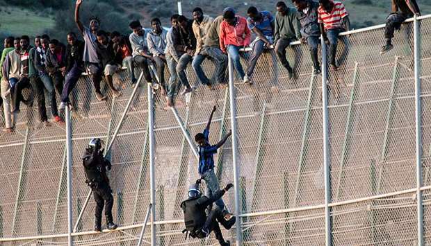 A member of the Spanish Civil Guard pulls a would-be immigrant off the border fence. File picture:  October 15, 2014