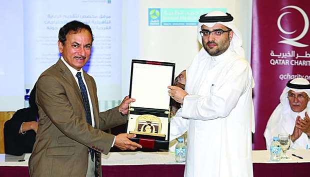 HMCu2019s Development of Physicians director Dr Abdulatif Mohamed al-Khal receiving a memento from Qatar Charityu2019s head of social programmes Farid Saddiqi.