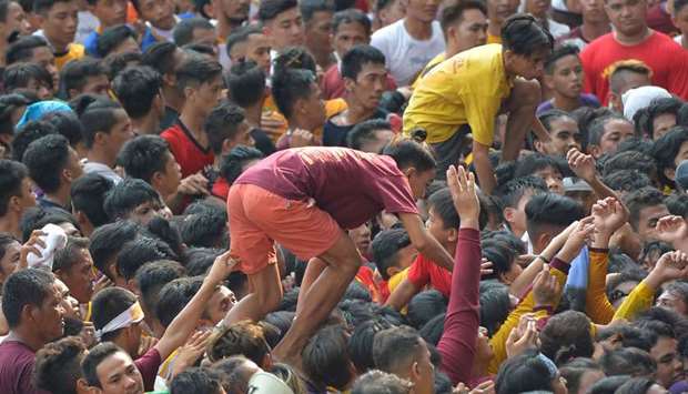 Young men walk amongst a sea of devotees as they try to climb onto a carriage carrying a replica of the Black Nazarene during a procession outside Quiapo church in Manila yesterday, ahead of the annual procession tomorrow.