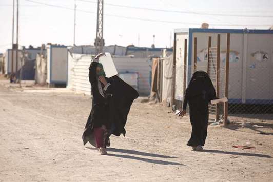 A displaced Iraqi woman carries a water container at the Amriyat Al Fallujah camp in Anbar Province.