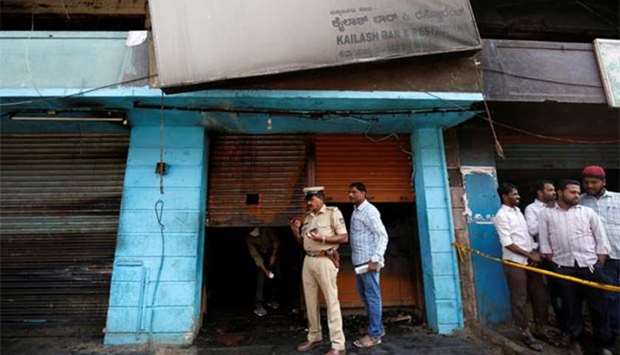 A police officer stands outside a burnt restaurant after a fire killed five people in Bengaluru on Monday.