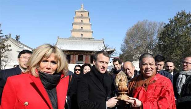 French President Emmanuel Macron is presented with a gift as his wife Brigitte Macron looks on during a tour around Big Wild Goose Pagoda in the northern Chinese city of Xian, Shaanxi province, on Monday.