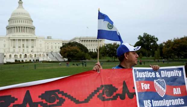 Salvadoran man holds flag and sign during a protest rally for immigrants rights on Capitol Hill in Washington