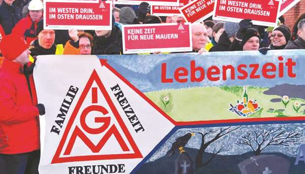 Workers of the Bombardier plant hold posters with the IG Metall logo as they stage a warning strike early yesterday in Hennigsdorf near Berlin, northeastern Germany. The words read u2018Family u2013 leisure time u2013 friends u2013 lifetimeu2019.