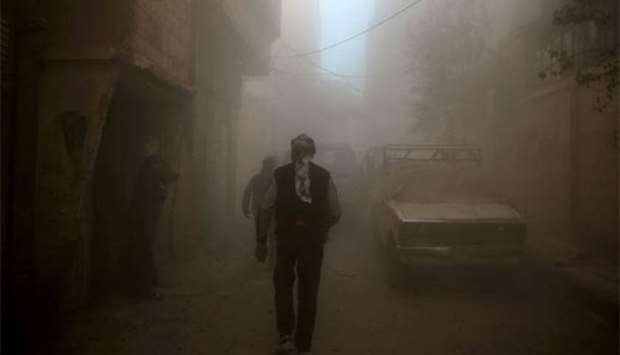 Syrian civilians walk amidst heavy dust and smoke in the rebel-held besieged town of Douma following air strikes in the eastern Ghouta region on the outskirts of Damascus on Monday.