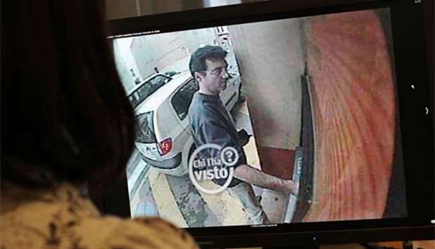 This file photo shows a woman looking at a still frame taken from a surveillance camera of Xavier Dupont de Ligonnes, a man suspected of murdering his wife and four children in Nantes in 2011, withdrawing cash from an ATM in Roquebrune-sur-Argens on April 14, 2011.
