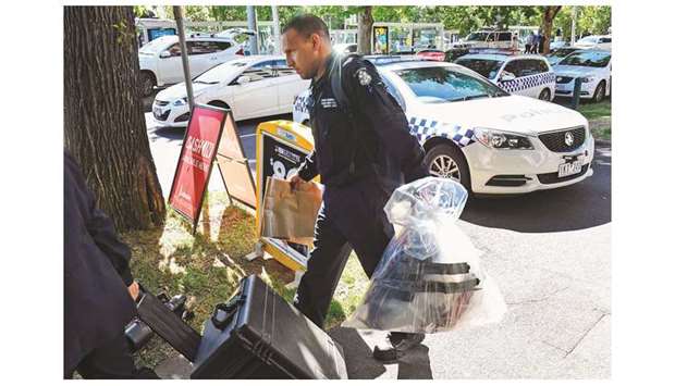 A Victoria Police forensic officer carries items to be loaded into a trailer outside the Italian consulate in Melbourne yesterday.