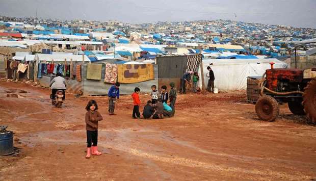 Children gather outside their makeshift shelters following torrential rain that affected a makeshift camp for displaced people near the town of Atme close to the Turkish border in Syria's mostly rebel-held northern Idlib province