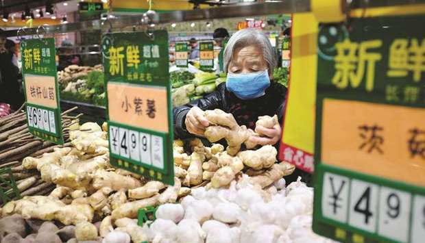 A resident selects ginger at a supermarket in Beijing. Chinau2019s consumer inflation for December eased from a year earlier due to lower non-food prices, data from the National Statistics Bureau showed yesterday.