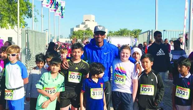 Qatari World high jump champion Mutaz Barshim with a group of child runners who joined the Ooredoo Doha Marathon.