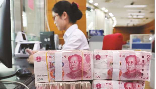 An employee counts 100 yuan notes at a bank in Nantong, Jiangsu province. The yuanu2019s 14-day relative strength against the dollar is at the highest since February 2018, reflecting a rise in buying momentum.