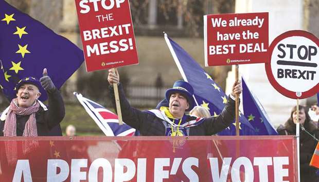 Anti-Brexit protesters hold signs outside the Houses of Parliament in London, yesterday.
