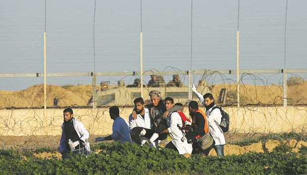 Palestinian medics evacuate a wounded demonstrator during a protest at the Israel-Gaza border fence, in the southern Gaza Strip yesterday.