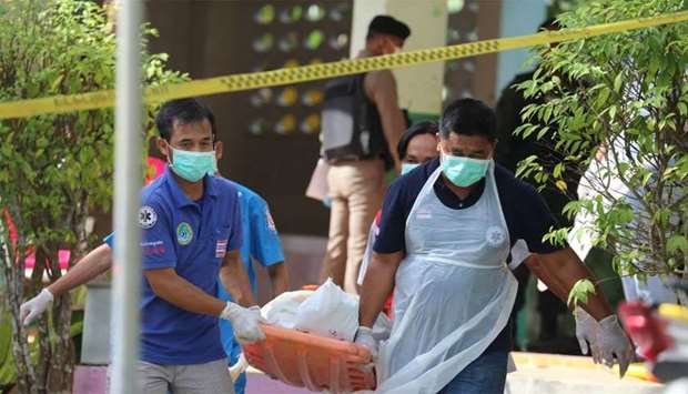 Paramedics take away a body after four Thai civil defence volunteers were shot and killed outside of a school in the restive southern province of Pattani