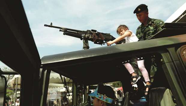A girl plays with a weapon on the top of an army vehicle during Childrenu2019s Day celebration at a military facility in Bangkok yesterday.