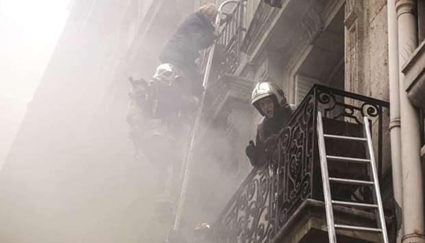 A woman is evacuated by firefighters after the explosion of a bakery on the corner of the streets Saint-Cecile and Rue de Trevise in central Paris.