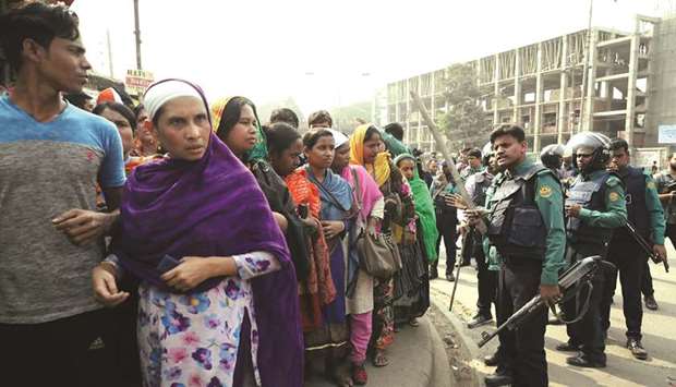 Police officers tell the garment workers who protest for higher wages to go to their workplace in Dhaka yesterday.