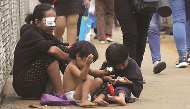 A woman begs as her children play at an overpass in Cubao, Quezon City.