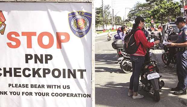 A policeman stops a bike rider at a checkpoint in Taguig City, Metro Manila.