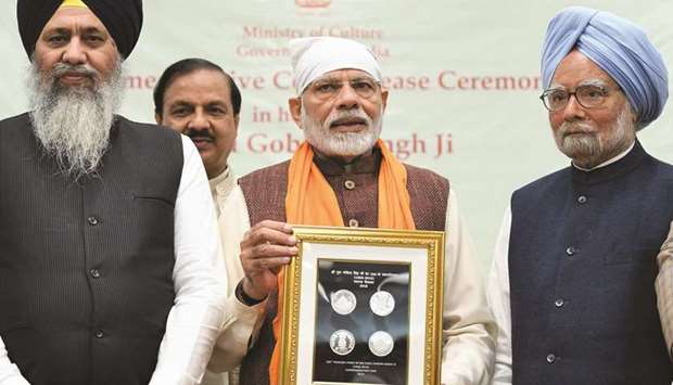 Prime Minister Narendra Modi releases a commemorative coin to mark the birth anniversary of tenth Sikh master, Guru Gobind Singh, in New Delhi yesterday as former prime minister Manmohan Singh looks on.