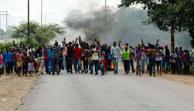 Angry protesters gesture as they block the main route to Zimbabwe's capital Harare from Epworth township