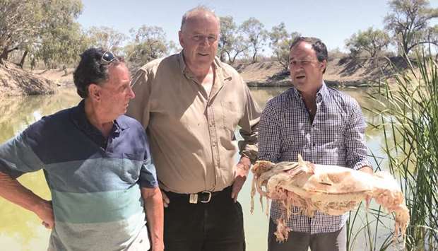 New South Wales member of parliament Jeremy Buckingham, right, holding a decades-old native Murray cod, which was killed during a massive fish kill in Menindee on the Darling River, as local residents Dick Arnold, left, and Rob McBride from Tolarno Station look on.