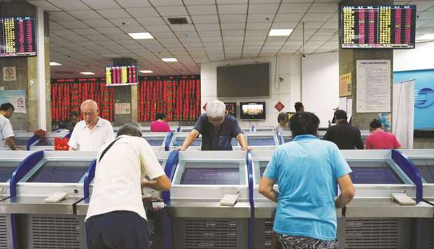 Investors look at computer screens showing stock information at a brokerage house in Shanghai. The Shanghai Stock Exchange ended up 1.4% at 2,570.34, with investors cheered by news of a range of tax cuts to support the stuttering Chinese economy.