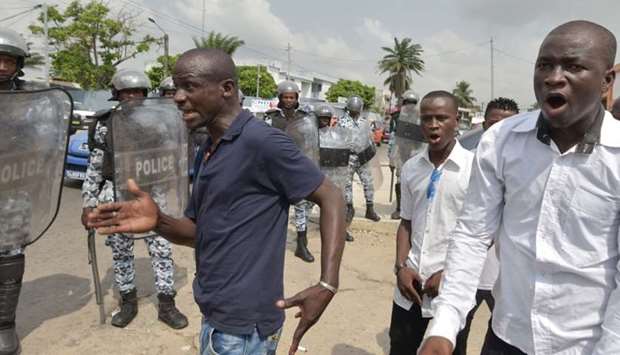 Men gesture as victims and relatives of victims of the 2011 post electoral violences arrive to protest against a request to release former Ivory Coast's president Laurent Gbagbo in front of the Conseil National des Droits de l'Homme