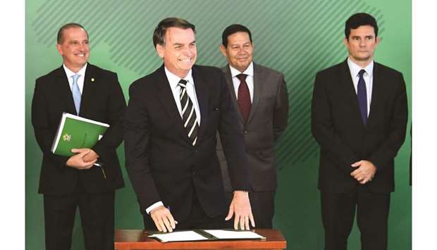 Brazilian President Jair Bolsonaro smiles as he signs a presidential decree that eases the possession of firearms, at Planalto Palace in Brasilia, yesterday.