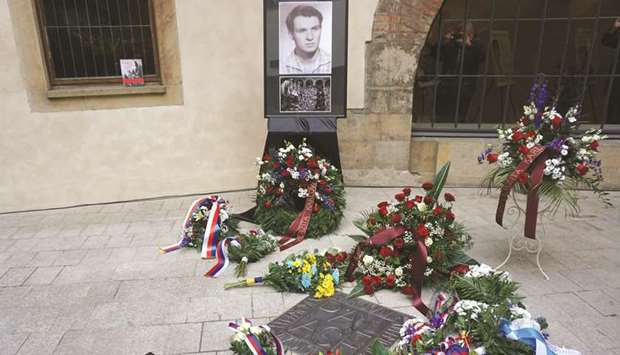 Flowers are placed next to a memorial plaque commemorating Jan Palach at Charles University in Prague.