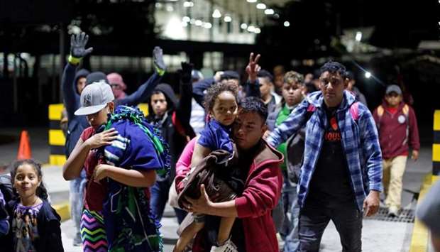 People belonging to a caravan of migrants from Honduras en route to the United States, walk at the border crossing to Mexico in Hidalgo, Mexico