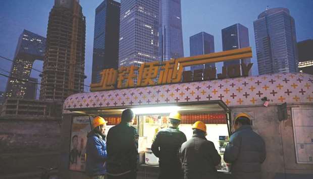 Construction workers buy snacks at a food stall in Beijingu2019s central business district. Chinau2019s economy grew at its slowest pace in almost three decades in 2018, analysts in an AFP poll said yesterday, as the government struggles to contain ballooning debt and a bruising trade war with the US.