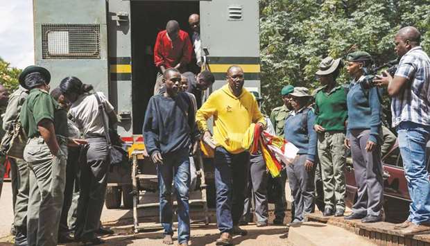 Zimbabwean cleric and activist Pastor Evan Mawarire, right, exits a prison truck as he arrives at the Harare Magistrates Court in Harare yesterday, for a court hearing on subversion charges.