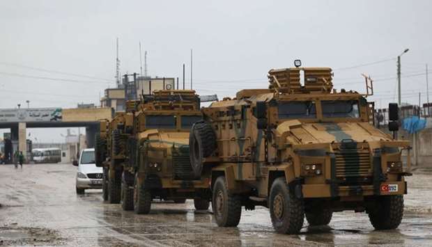 Turkish military vehicles ride at the Bab el-Salam border crossing between the Syrian town of Azaz and the Turkish town of Kilis, in Syria