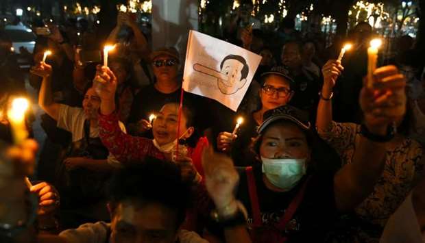 A placard mocking Thailand's Prime Minister Prayuth Chan-o-cha as Pinocchio is seen as activists hold up candles while gathering to demand quick elections to end military rule at a university in Bangkok