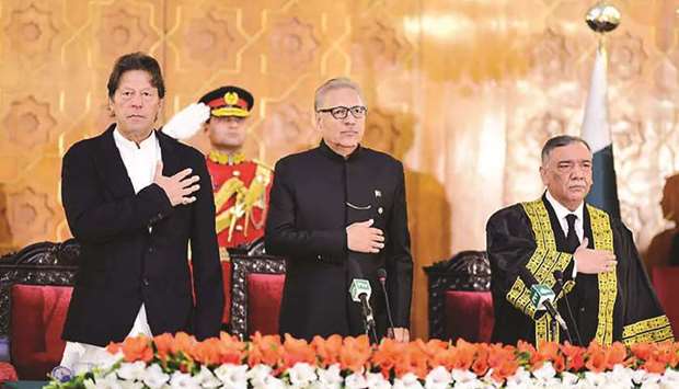 In this handout photo released by the Prime Ministeru2019s Office yesterday, Prime Minister Imran Khan, President Arif Alvi and newly appointed Chief Justice of the Pakistan Supreme Court Asif Saeed Khosa stand for the national anthem during the oath-taking ceremony for new chief justice in Islamabad.