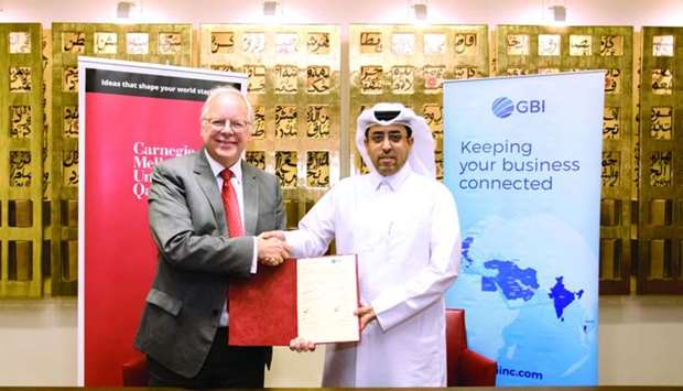 CMU-Q and GBI officials shake hands after signing an MoU