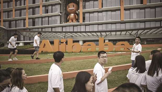 Employees and visitors walk past a signage for Alibaba Group Holding at the companyu2019s headquarters in Hangzhou. Chinau2019s largest e-commerce company is cutting its spending on travel and postponing some new hiring as Chinau2019s largest e-commerce company braces for a slowing economy, people familiar with the matter said.