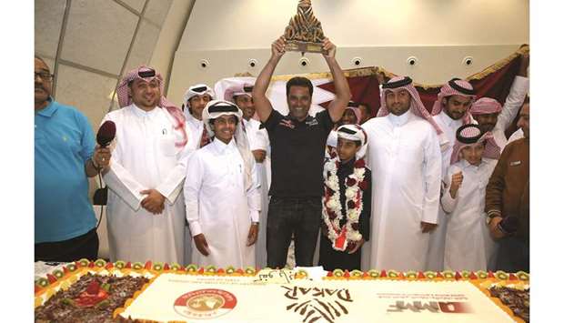 Qataru2019s three-time Dakar Rally champion Nasser al-Attiyah lifts his trophy during a welcome ceremony on his arrival at Hamad International Airport yesterday.