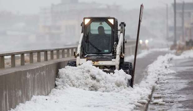 A worker uses a bobcat to clear snow from a sidewalk alongside Nantasket Beach during a winter storm that brought snow, sleet and rain to the area yesterday in Hull, Massachusetts