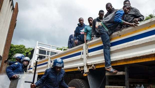 Zimbabwean anti-riot police escorts men, arrested during violent protests triggered by a sudden rise in fuel prices announced by Zimbabwean President, for their hearing at the Law Court in the capital Harare, on January 16.