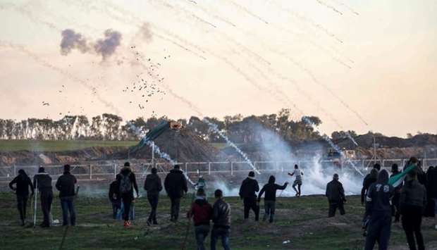 Tear gas canisters falling amidst Palestinian protesters during clashes with Israeli forces across the border fence, following a demonstration along the border with Israel east of Gaza City on January 18.