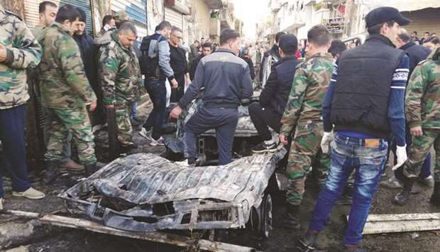 This handout image made available by the official Syrian Arab News Agency (SANA) yesterday, shows onlookers and security forces gathered around a burnt vehicle in the city of Latakia.