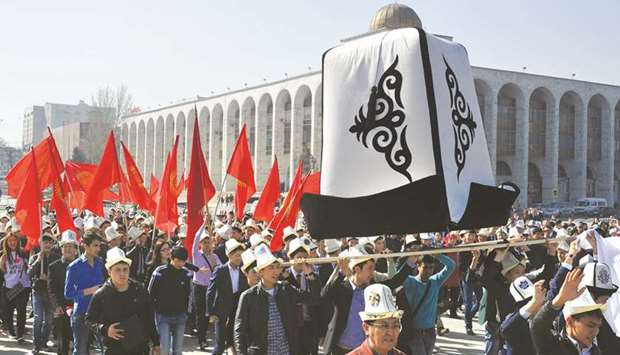 In this file photo taken on March 5, 2016, Kyrgyz people wear traditional hats and carry a big Kyrgyz cap (Ak-Kalpak) and national flags during a rally marking u2018National Flag Dayu2019 and u2018Kyrgyz Cap Dayu2019 at the central Ala-Too Square in Bishkek.