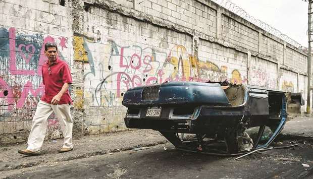 A man walks by a car that was vandalised in Caracas on Tuesday.