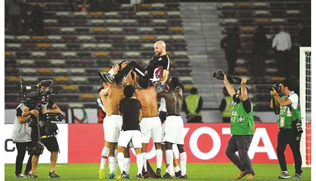 Qatar players lift coach Felix Sanchez (also top) in celebration of their victory over South Korea in their AFC Asian Cup quarter-final in Abu Dhabi yesterday. (AFP)