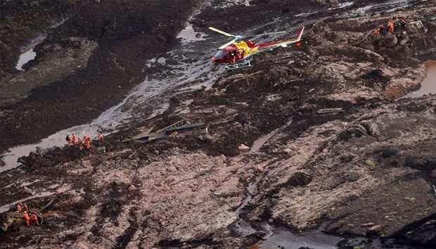Aerial view showing firemen looking for people in heavy machinery (L and R) and a locomotive (C) after the collapse of a dam which belonged to Brazil's giant mining company Vale
