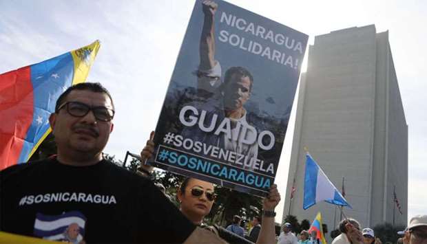 Anti-Maduro demonstrators gather as one holds a poster of Venezuelan opposition leader Juan Guaido